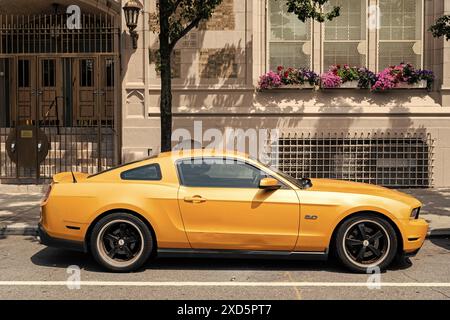 New York City, USA - August 05, 2023: 2011 Ford Mustang V6 yellow car passenger side view, parked Stock Photo
