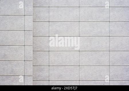 Close up of a tiled wall with a grid pattern, featuring light gray tiles and dark grout lines, as texture, background. Stock Photo