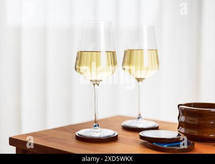 Romantic party with two glasses of delicious white wine in a cozy living room with a Scandinavian style interior. Copy space. Stock Photo