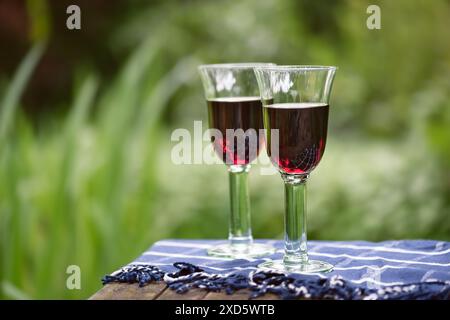 Two glasses of red wine on garden table garden background. Romantic celebration concept. Stock Photo