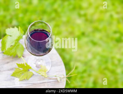 Top view of a glass with red wine stand on the wooden table  in the garden. Alcoholic drinks. Camping. Picnic. Cold white wine. Rest for two. Warm eve Stock Photo