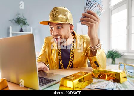 Rich Man Holding Cash Stack, Using Laptop And Celebrating Financial Success Stock Photo