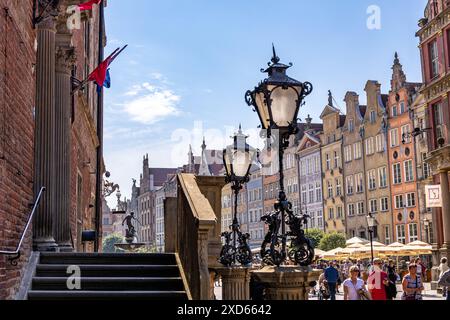 Tourists walking on Długa Street in Gdansk, with historic street lamps and colorful facades in the background. Stock Photo