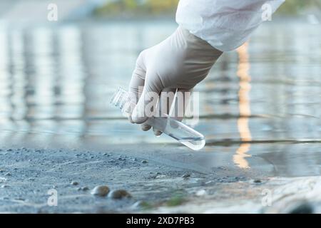 Close up of scientist with white glove holding test tube with water in his hand. Water pollution examine concept Stock Photo