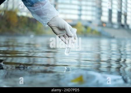 Close up of scientist with white glove holding test tube with water in his hand. Water pollution examine concept Stock Photo