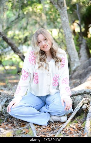 A trendy  young woman with wavy blonde hair sitting outdoors, we Stock Photo