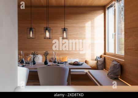 Modern dining area with elegant table setting and cozy wooden decor Stock Photo