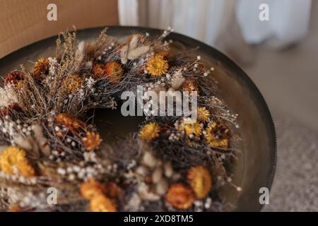 Rustic wreath of dried flowers and grasses on a metal tray Stock Photo