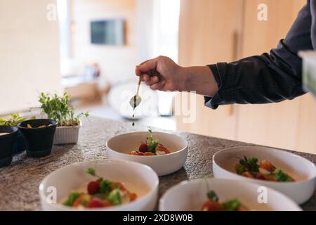 Chef garnishing gourmet dishes with sauce in a modern kitchen Stock Photo