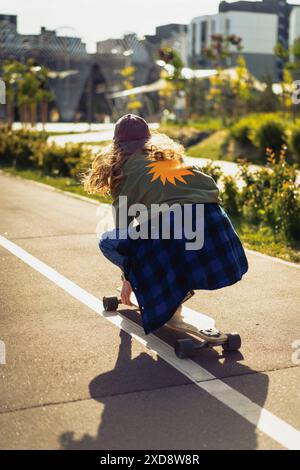 Young woman rides a longboard along the city streets. Stock Photo