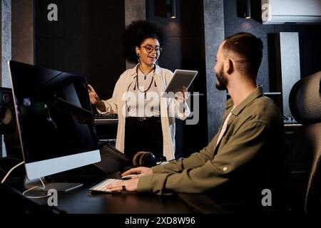 A man and woman collaborate in a professional recording studio to rehearse music for their bands upcoming performance. Stock Photo