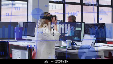 Image of statistical data processing against caucasian woman wearing vr headset at office Stock Photo