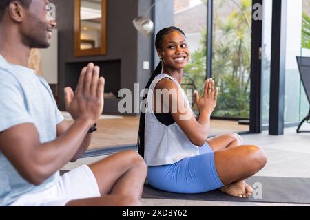 Practicing yoga together, young couple sitting on mats and smiling at each other Stock Photo