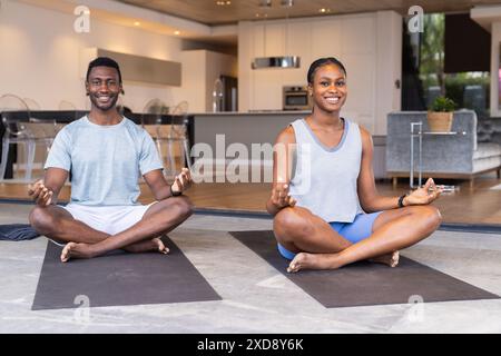 Practicing yoga together, young couple sitting cross-legged on mats at home Stock Photo