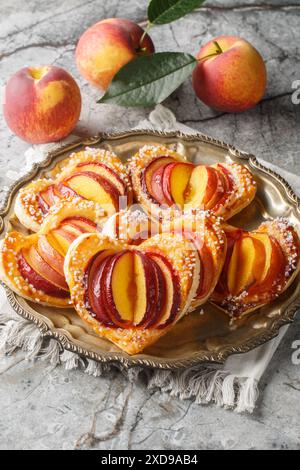 Baked Peach puff pastry cakes with fresh fruit and jam close-up in a plate on the table. Vertical Stock Photo