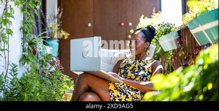 Portrait of smiling woman using laptop while sitting on the balcony Stock Photo