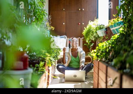 Portrait of smiling woman using laptop while sitting on the balcony Stock Photo