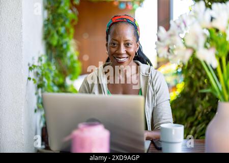 Portrait of smiling woman using laptop while sitting on the balcony Stock Photo