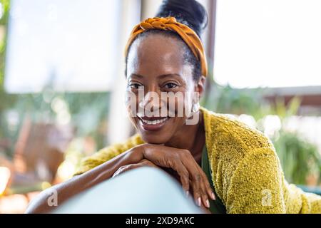 Portrait of smiling woman relaxing on sofa at home, looking at camera Stock Photo