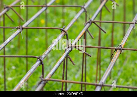 Reinforcement cages lay on green grass at construction site, abstract industrial background photo Stock Photo