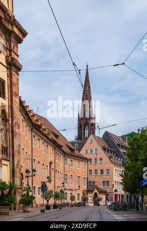 Freiburg im Breisgau, Germany, July 23, 2023, Tramway rail tracks alongside historical old town buildings with view to famous muenster cathedral steep Stock Photo