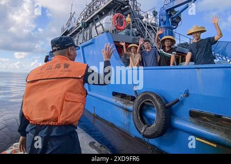 (240621) -- SANSHA, June 21, 2024 (Xinhua) -- A law enforcer of China Coast Guard waves goodbye to Chinese fishermen after returning the retrieved fishing nets in China's Ren'ai Jiao and the surrounding territorial sea, June 11, 2024. Recently, in China's Ren'ai Jiao and the surrounding territorial sea, personnel from the illegally grounded Philippine navy transport ship repeatedly damaged Chinese fishermen's nets and deployed the illegally obtained fishing nets to the nearby waters of their ship to obstruct the law enforcement of China Coast Guard (CCG).  CCG law enforcers have retrieved thes Stock Photo