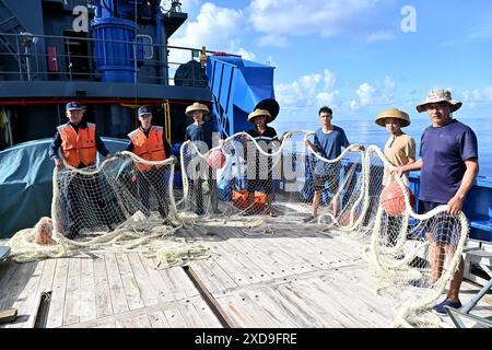 (240621) -- SANSHA, June 21, 2024 (Xinhua) -- Law enforcers of China Coast Guard (1st and 2nd, L) and Chinese fishermen pose for photos with retrieved fishing nets on a fishing boat in China's Ren'ai Jiao and the surrounding territorial sea, June 11, 2024. Recently, in China's Ren'ai Jiao and the surrounding territorial sea, personnel from the illegally grounded Philippine navy transport ship repeatedly damaged Chinese fishermen's nets and deployed the illegally obtained fishing nets to the nearby waters of their ship to obstruct the law enforcement of China Coast Guard (CCG). CCG law enforce Stock Photo