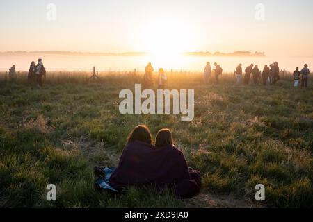 Spiritually-minded revellers celebrate the summer Solstice (mid-summer and longest day) at the stones at the ancient late-Neolithic stones of Stonehenge, on 21st June 2024, in Wiltshire, England. The summer solstice is the northern hemisphere's longest day and shortest night of the year, when the earth’s axis is tilted at its closest point from the sun and pagans say the ancient monument is a sacred place that links the Earth, Moon, Sun and the seasons. Stonehenge was built in three phases between 3,000 B.C. and 1,600 B.C. Stonehenge is owned by English Heritage who say 15,000 visitors were al Stock Photo