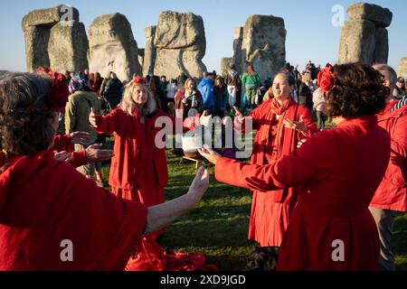 Spiritually-minded revellers celebrate the summer Solstice (mid-summer and longest day) at the ancient late-Neolithic stones of Stonehenge, on 21st June 2024, in Wiltshire, England. The summer solstice is the northern hemisphere's longest day and shortest night of the year, when the earth’s axis is tilted at its closest point from the sun and pagans say the ancient monument is a sacred place that links the Earth, Moon, Sun and the seasons. Stonehenge was built in three phases between 3,000 B.C. and 1,600 B.C. Stonehenge is owned by English Heritage who say 15,000 visitors were allowed into the Stock Photo