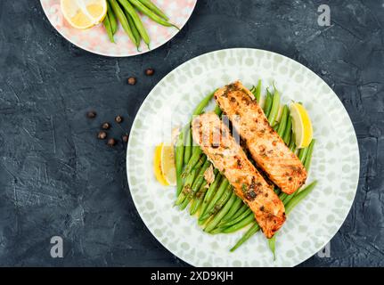 Savoury baked salmon fillets garnished with bush green beans on a concrete kitchen table. Top view. Stock Photo