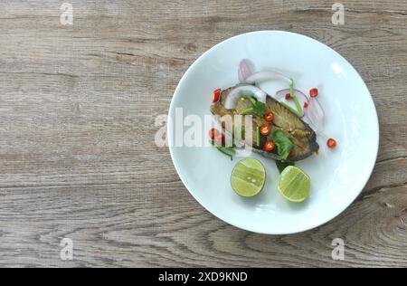 salty dry Indo-Pacific king mackerel fish topping chop shallot and chili with slice lemon salad on plate Stock Photo
