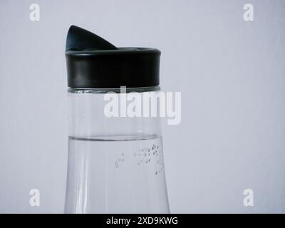 Glass bottle with water on a white background close-up. Air bubbles in water on the wall of the carafe. Stock Photo