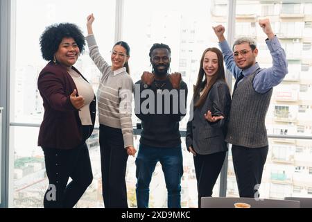 Portrait of different ethnicities business people in the office standing celebrating the great increase in monthly sales achieved, are making gestures Stock Photo