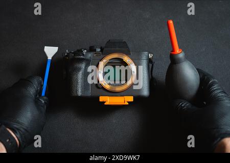 Cleaning the sensor of a photo camera. Male hands in rubber gloves hold a camera sensor maintenance kit. Stock Photo