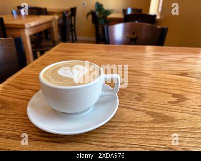 Coffee cup with heart shape latte art on wooden table in coffee shop Stock Photo