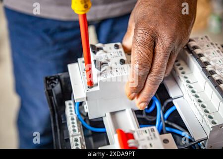 Close-up hand of a electrician working with a screwdriver on a industrial panel mounting and assembling new wiring on breakers. Stock Photo