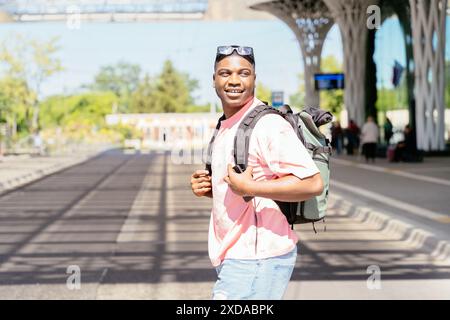 A man wearing a pink shirt and a backpack is walking down the street. He is smiling and he is happy. Stock Photo
