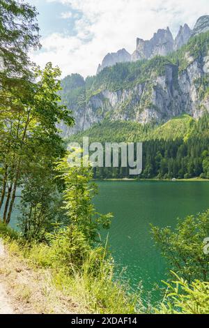 View of a tranquil lake, surrounded by green forests and high mountains under a clear sky, gosau, austria Stock Photo
