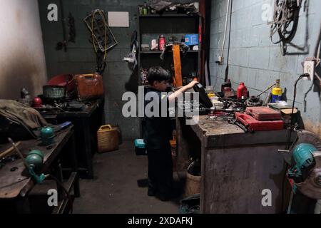 Maracaibo, Venezuela.5-14-2024. Alejandro Matias arrives at his father’s workshop after school to help his father as mechanic. Photo By. Jose I. Bula Stock Photo