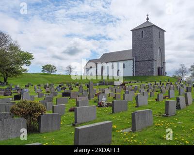 Stone church on a hill with surrounding cemetery and many gravestones in peaceful nature, haugesund, norway Stock Photo