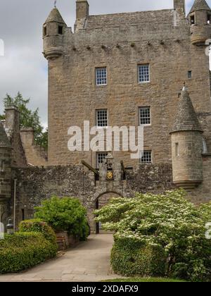 A Historic Castle With Tower, Surrounded By A Green Meadow And Blue Sky 