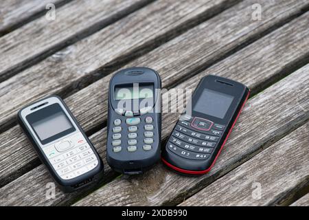 Old cell phones on old weathered wooden table Stock Photo