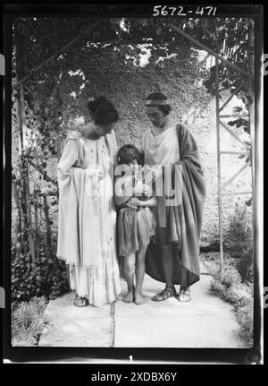 Kanellos, Vanellos and Tanagra, and child holding a cat, in dance costumes. Genthe photograph collection. Stock Photo