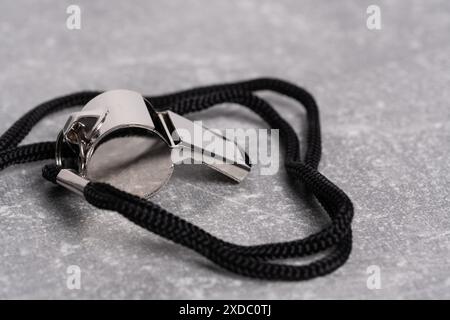 Referee whistle with a black rope on a gray background close up Stock Photo