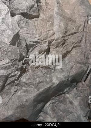 A close-up photograph of wrinkled gray tissue paper with a textured surface. The paper is folded and creased, creating a natural, organic pattern. Stock Photo