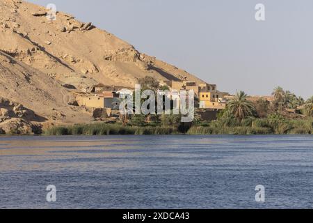 A timeless Egyptian village perches like an oasis on the banks of the river Nile at the foot of an arid sandstone hill between Luxor and Esna. Stock Photo