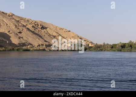 A timeless Egyptian village perches like an oasis on the banks of the river Nile at the foot of an arid sandstone hill between Luxor and Esna. Stock Photo