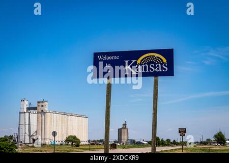 Elkhart, KS, USA - May 30, 2024: A Welcome to Kansas state line sign with a rural landscape in the background, featuring industrial buildings and a cl Stock Photo