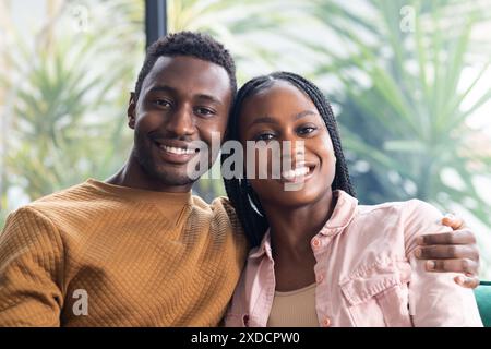 Young African American couple sits closely, smiling and enjoying their time at home Stock Photo