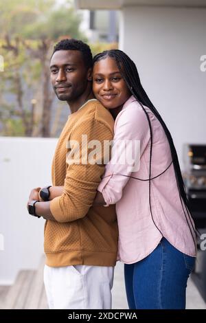 Young couple standing on balcony, embracing and smiling Stock Photo